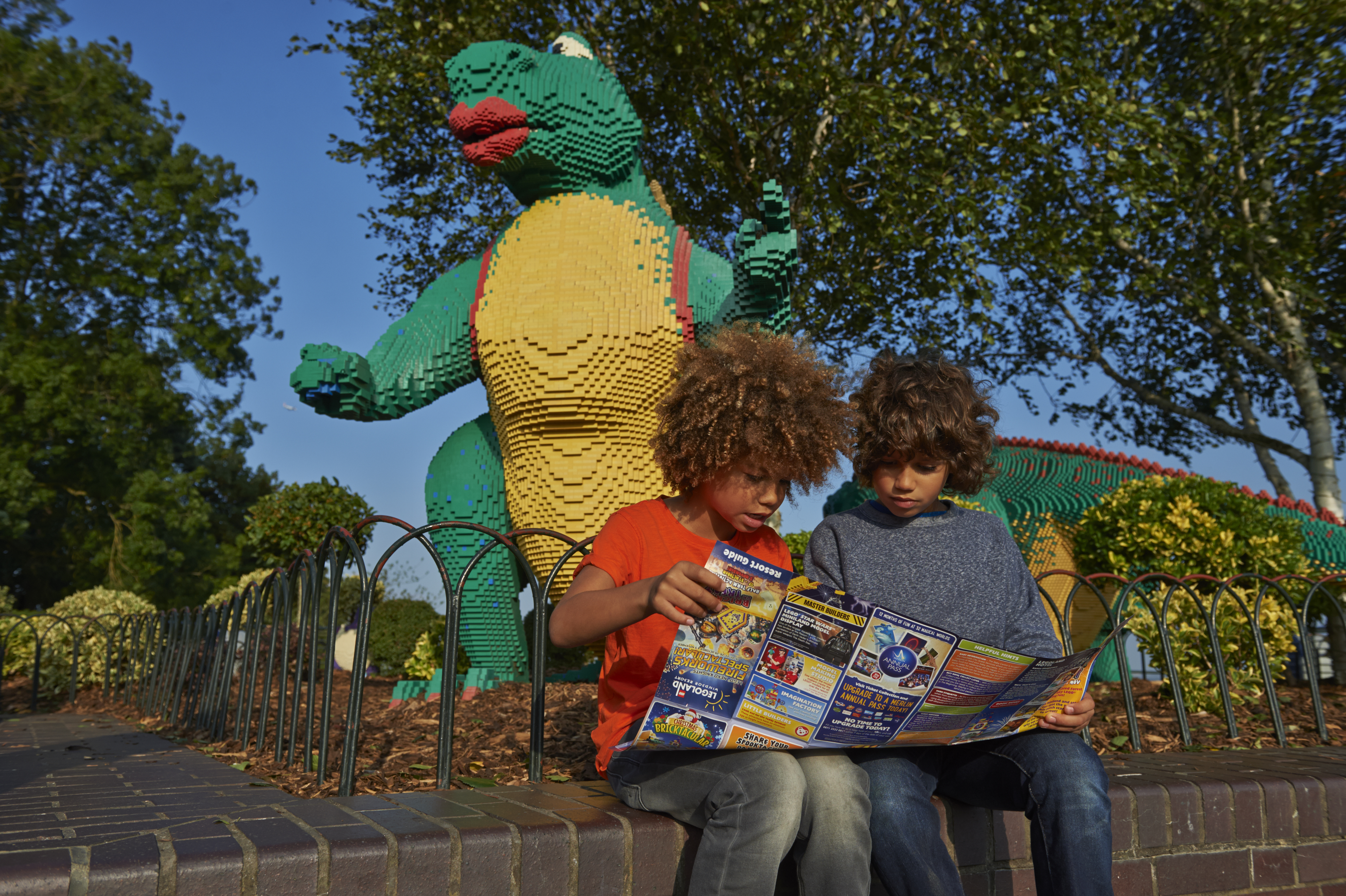 Children looking at map in front of LEGO model of a dinosaur