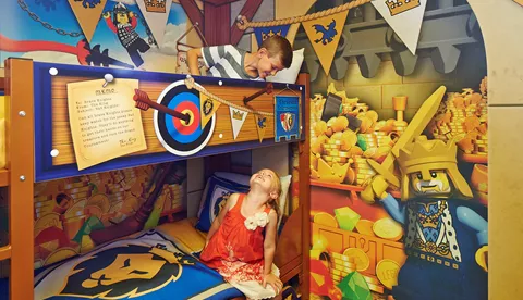 Children smiling at each other on bunk beds in a Knight's room in the LEGOLAND Castle Hotel