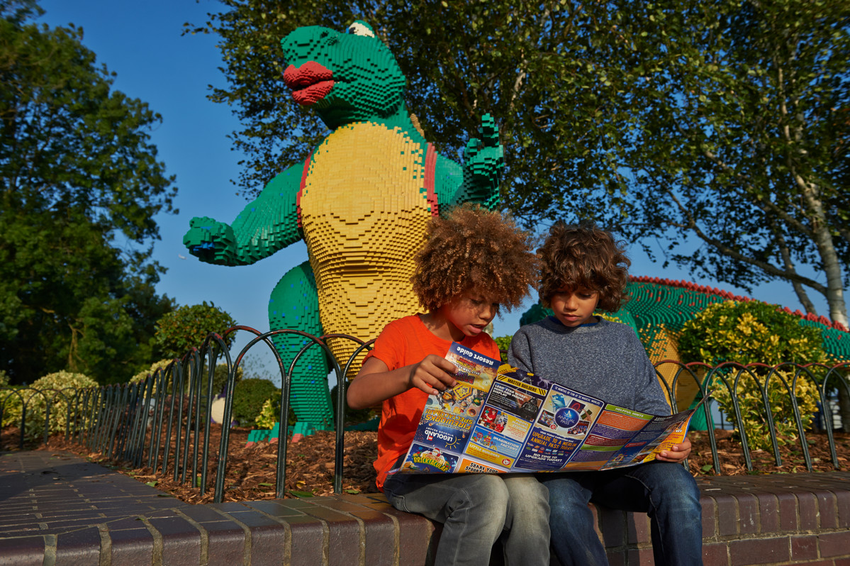 Children looking at map in front of LEGO model of a dinosaur