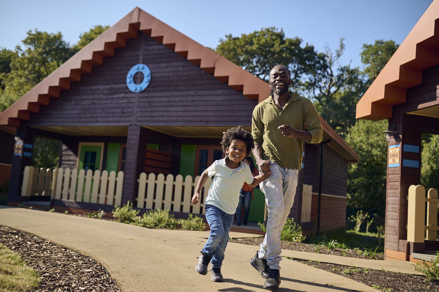 Father and son outside of a standard lodge running through the LEGOLAND Wooland Village in Windsor